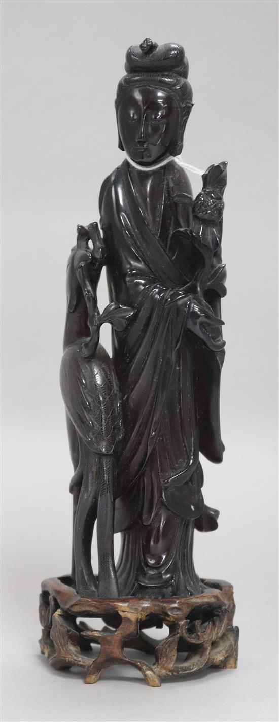 A Chinese faux amber standing figure of Xi Wangmu with a phoenix, wood stand, 23.5cm